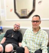 James Argentino and Julio Mungia sit side by side on a couch in their home