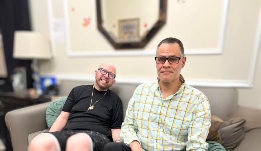 James Argentino and Julio Mungia sit side by side on a couch in their home