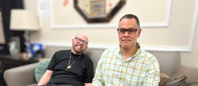 James Argentino and Julio Mungia sit side by side on a couch in their home