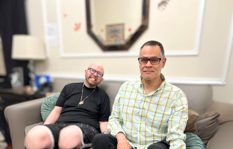 James Argentino and Julio Mungia sit side by side on a couch in their home