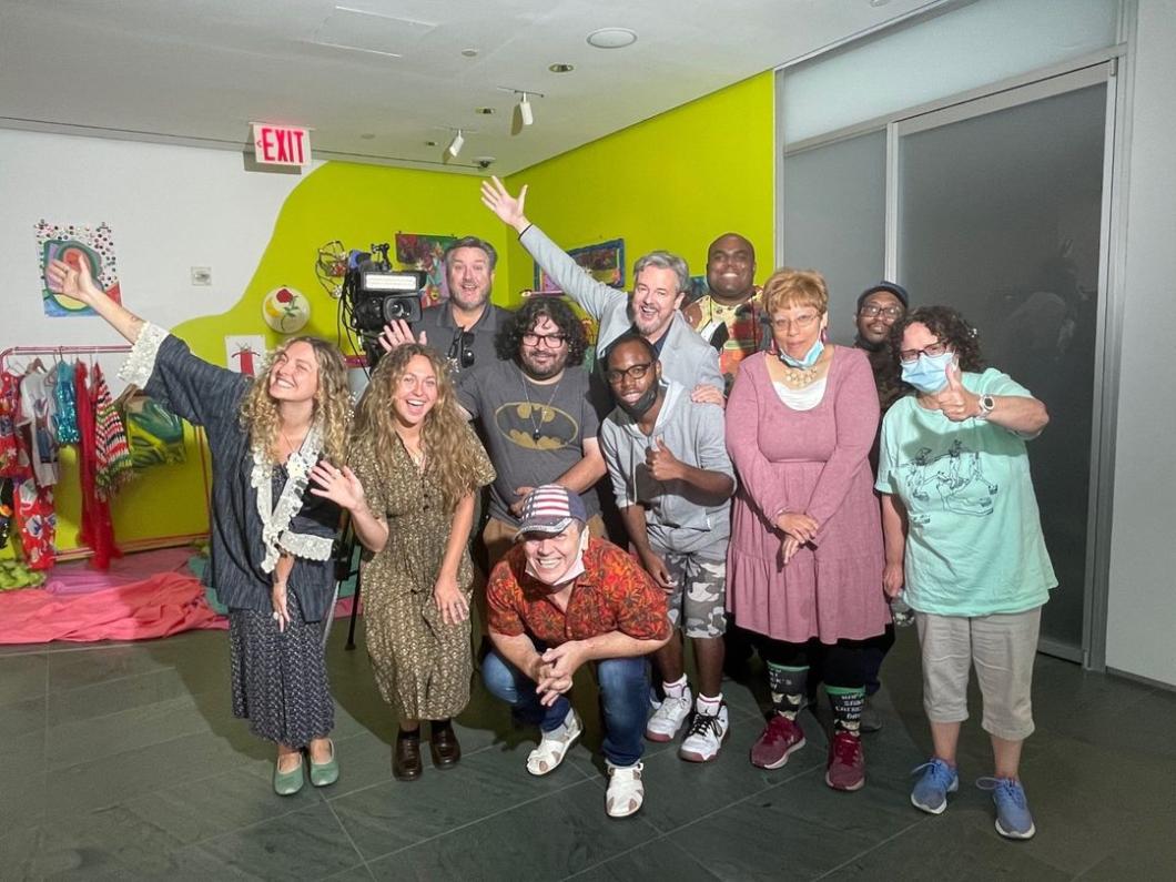 Group of people pose, some with arms, in front of an art installation at the MoMA