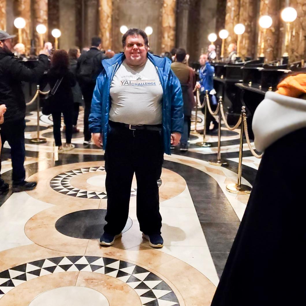 Richard stands in a hallway with others standing around in the background