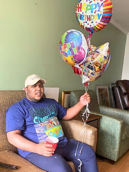 Jadon sitting on a chair holding birthday balloons