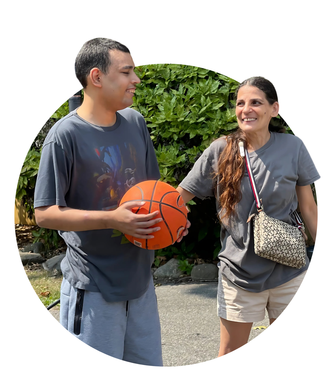 Young man holds a basketball while his mother looks on