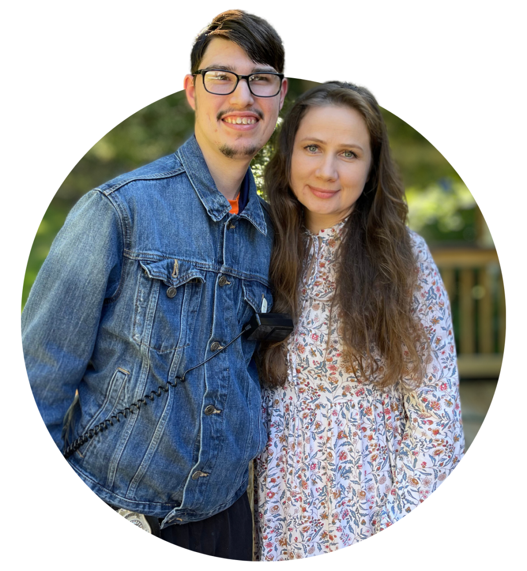 Man in glasses stands next to woman with long hair, they are both posing for photo