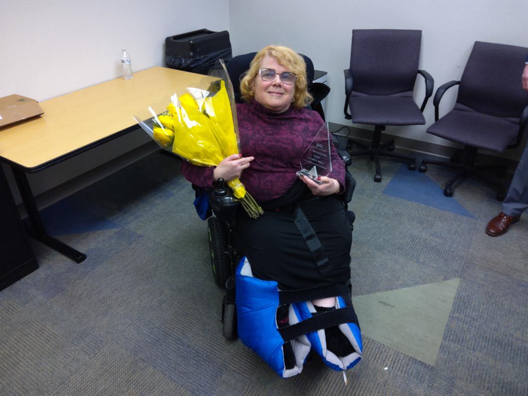 Stephanie is in a wheelchair and holding a bouquet of flowers as she poses for photo